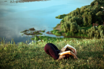 Yoga practice and meditation in nature in sunrise. Woman practicing near big river Kama.