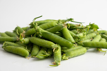 Pods of fresh young green peas close up on a white background