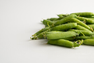 Pods of fresh young green peas close up on a white background
