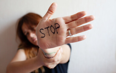 A woman protects herself with the palm of her hand written "Stop"