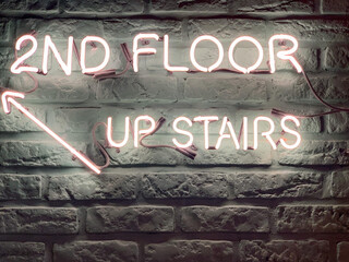 there's a neon sign on a wall that says "2nd Floor upstairs"