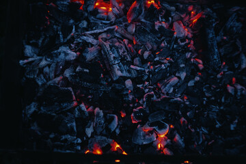 Red hot coals, lit a fire to cook a barbecue. Texture fire bonfire embers.The hot embers of burning wood log fire. Firewood burning on grill.