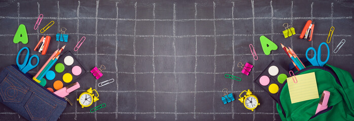 Back to school background with bag backpack, pencil case and school supplies over chalkboard. Top...