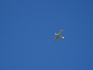 white small airplane flies in the cloudless blue sky
