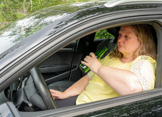 Frau trinkt Alkohol im Auto am Lenkrad