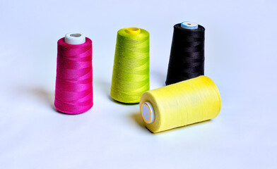 Four sewing thread rolls in different colors isolated on white