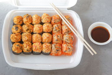 Set Japanese sushi with soy sauce and chopsticks on a grey concrete background. Restaurant food delivery. Top view.