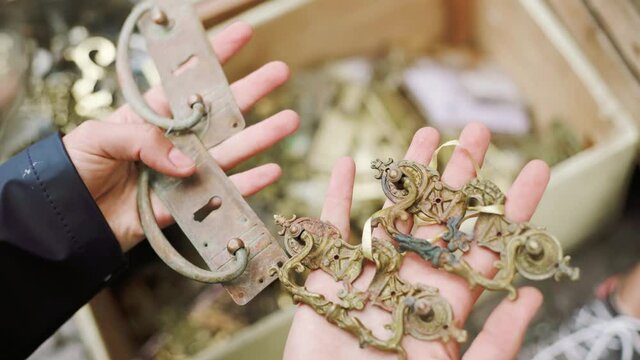 Searching through antique locks and handles at flea market/antique store