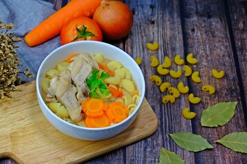 Delicious chicken macaroni soup served on wood tray.