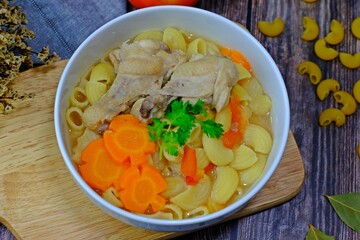 Delicious chicken macaroni soup served on wood tray.