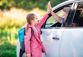 Schooler giving five to father in car