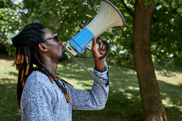side view on young african man shouting on loudspeaker during demonstartion in the street. black...