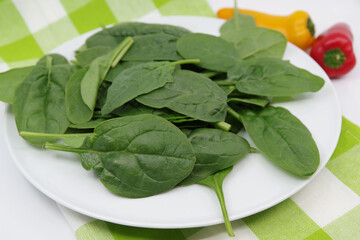 Fresh spinach leaves in a plate. Juicy spinach leaves. Spinach green fresh leaves. Small sweet peppers