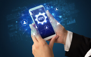Female hand holding smartphone with OTT abbreviation, modern technology concept