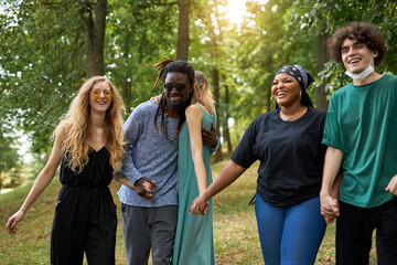 make love, not war, be tolerant. friendly group of mixed race people have fun outdoors, diverse men and women have rest, communicate and laugh in the park