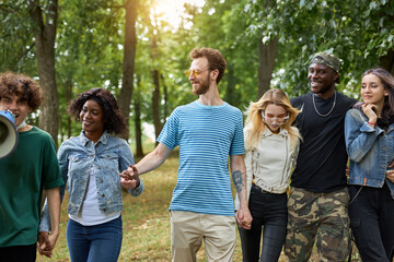 happy diverse african and caucasian people walk together in the park, have conversation and laugh....