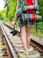 Fototapeta premium Legs of a woman with a backpack walk along the railway tracks with binoculars.