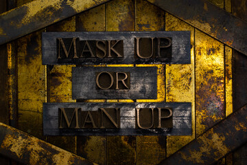 Mask Up or Man Up text formed with real authentic typeset letters on vintage textured silver grunge copper and gold background