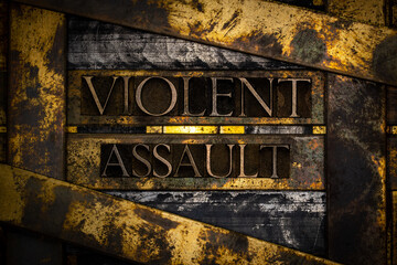 Violent Assault text formed with real authentic typeset letters on vintage textured silver grunge copper and gold background