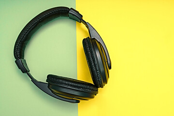 Large, black headphones lie on a colored background. Device for individual listening to music.