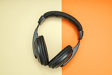 Large, black headphones lie on a colored background. Device for individual listening to music.