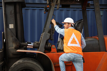 Fototapeta na wymiar A engineering or technician is working at container stock yard, radio mobile talking communication with loader forklift for transport handling inspection check or maintenance