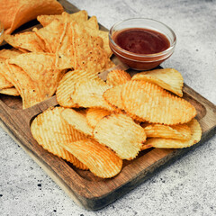 Chips, snacks and crackers on a wooden board. Fast food.