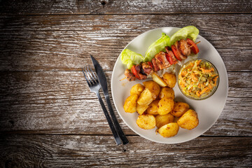 Shish kebab served with roasted potatoes and salad.