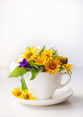 Flowers composition. Yellow flowers heliopsis in a white cup close up on the white background. Copy space