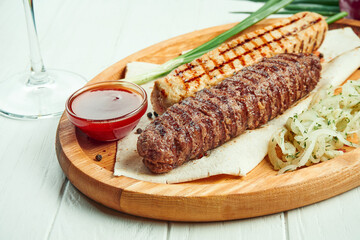 Classical arabic beef or chicken Lula Kebab with onion garnish on wooden board. Appetizing meat on the grill. White background.