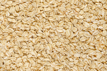 Rolled oats, close-up. Lightly processed whole-grain food. Husked and steamed oat groats rolled into flakes and lightly toasted to stabilize. Food photo, top view, from above, surface and background.