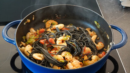 Garnelen mit schwarzen Spagetti in blauer Pfanne /
Shrimp with black spagetti in a blue pan
