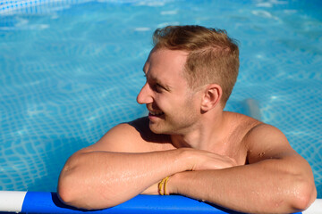 Smilling man is resting in the pool. Isolated summer rest during the coronavirus period. Cottagecore