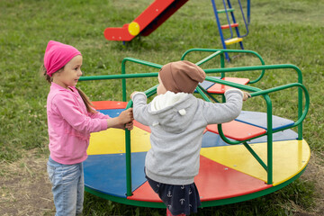 Obraz premium Two little girls have fun on a carousel outdoors
