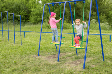 Two little girls have fun on a swing outdoors