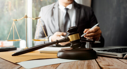 Justice and law concept.Male judge in a courtroom with the gavel, working with, computer and docking keyboard, eyeglasses, on table in morning light