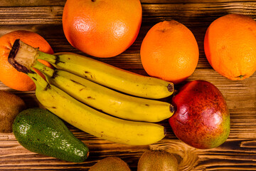 Still life with exotic fruits. Bananas, mango, oranges, avocado, grapefruit and kiwi fruits on wooden table. Top view