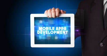 Young business person working on tablet and shows the inscription: MOBILE APPS DEVELOPMENT