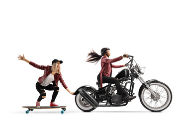 Obraz na płótnie Canvas Female biker riding a chopper and pulling a female on a skateboard