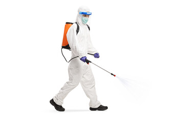 Man in a hazmat suit walking and spraying a sanitizer