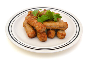 Cooked sausages arranged in white plate on white background