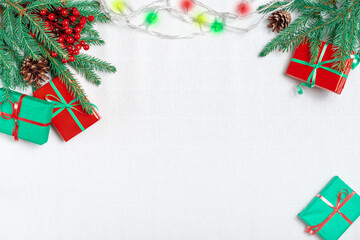 Fototapeta na wymiar Beautiful Christmas holiday frame of fir branches, gift boxes decorated by christmas lights.