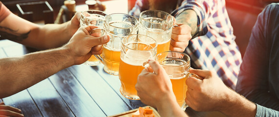 Group of friends toasting with beer in pub, closeup. Banner design