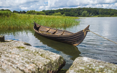Kleines Wikinger Boot im Wasser, an einem Steg angeleint, im Museum von Haithabu bei Schleswig