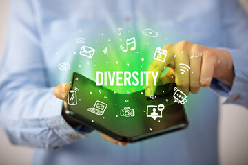 Businessman holding a foldable smartphone with DIVERSITY inscription, social media concept