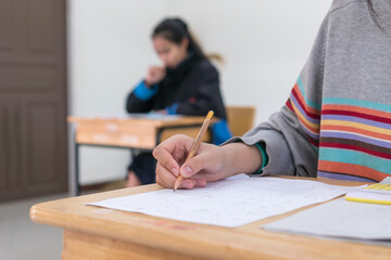 Woman Asian Hands Student testing in exam on exercise taking at high school or university in test room and Writing document exams classroom, back to school and evaluation measurement in education