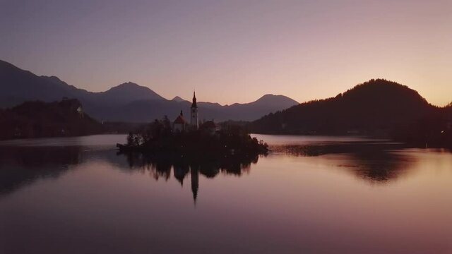 Flight around of Bled Island (Blejski otok) with pilgrimage church of the Assumption of Mary and Bled castle on Lake Bled at clear autumn morning, Slovenia