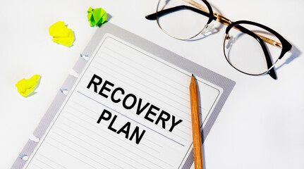 ON a sheet from the diary is the inscription RECOVERY PLAN, next to glasses and pencil.