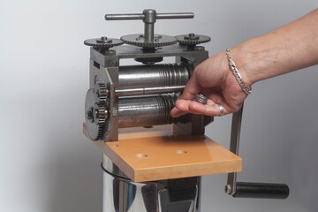 Jeweler at work, process rolling of a silver wire crafting in a jewelery workshop.