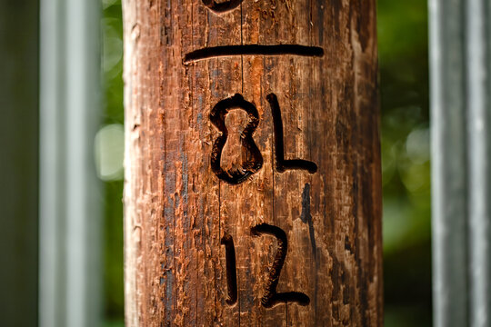 The letters, B and L along with the numbers 1 and 2 carved into a wooden post.